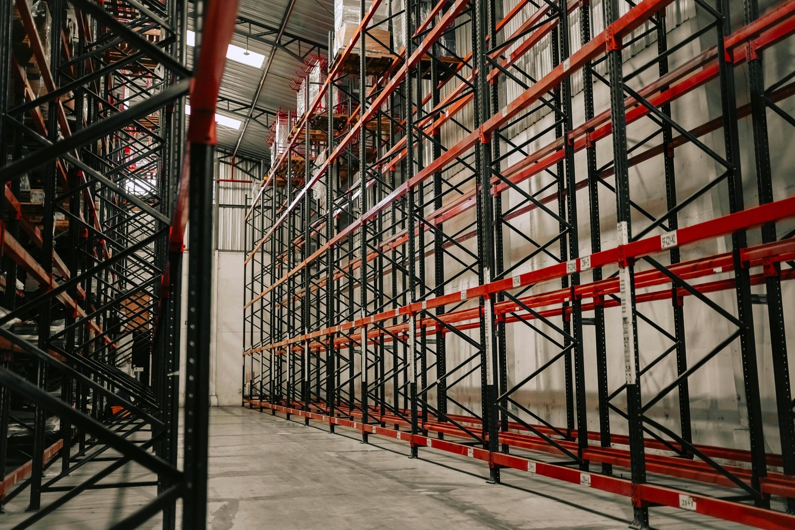 Spacious warehouse interior featuring empty metal racks and high ceiling.